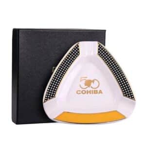 Κεραμικό Σταχτοδοχείο για 3 Πούρα (ASH-110) άσπρο με λογότυπο Cohiba και διακοσμητικές λεπτομέρειες σε κίτρινο και μαύρο διχτυωτό δίπλα από το μαύρο κουτί του