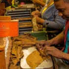 εργάτης κατασκευάζει ένα πούρο σε εργοστάσιο πούρων