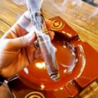 OLIVA - Serie V Melanio Limitada 2023 Figurino, χέρι που κρατάει αναμμένο πούρο που βγάζει καπνό πάνω από τασάκι